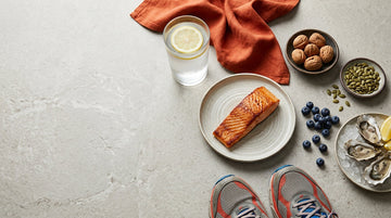 Glass of water, salmon, pumpkin seeds, blueberries and walnuts on a light kitchen counter